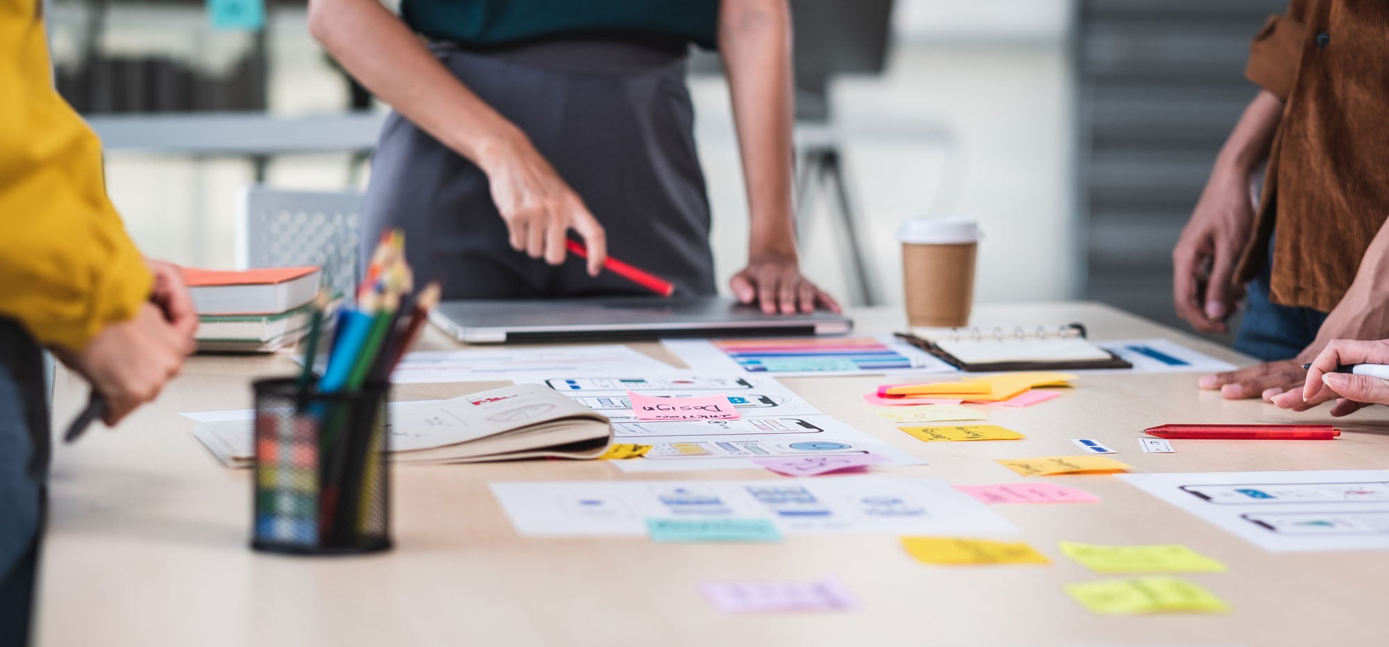 Close up UX developer and UI designer brainstorming about interface wireframe design on table with customer brief and color code at modern office