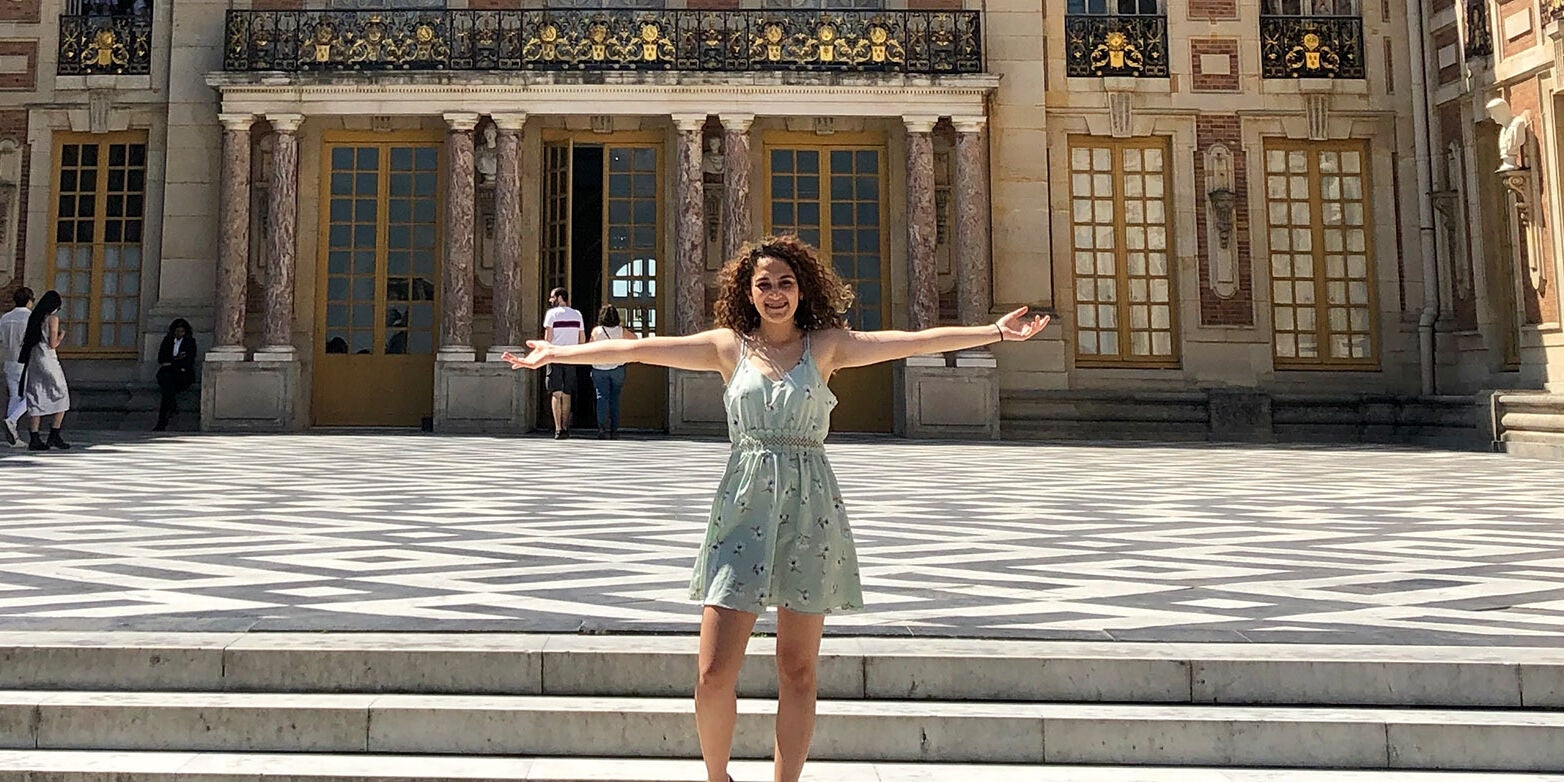 Jackie poses in front of the Château de Versailles in Paris, France